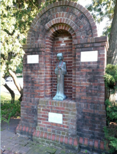 A statue of a child surrounded by a closed brick archway.